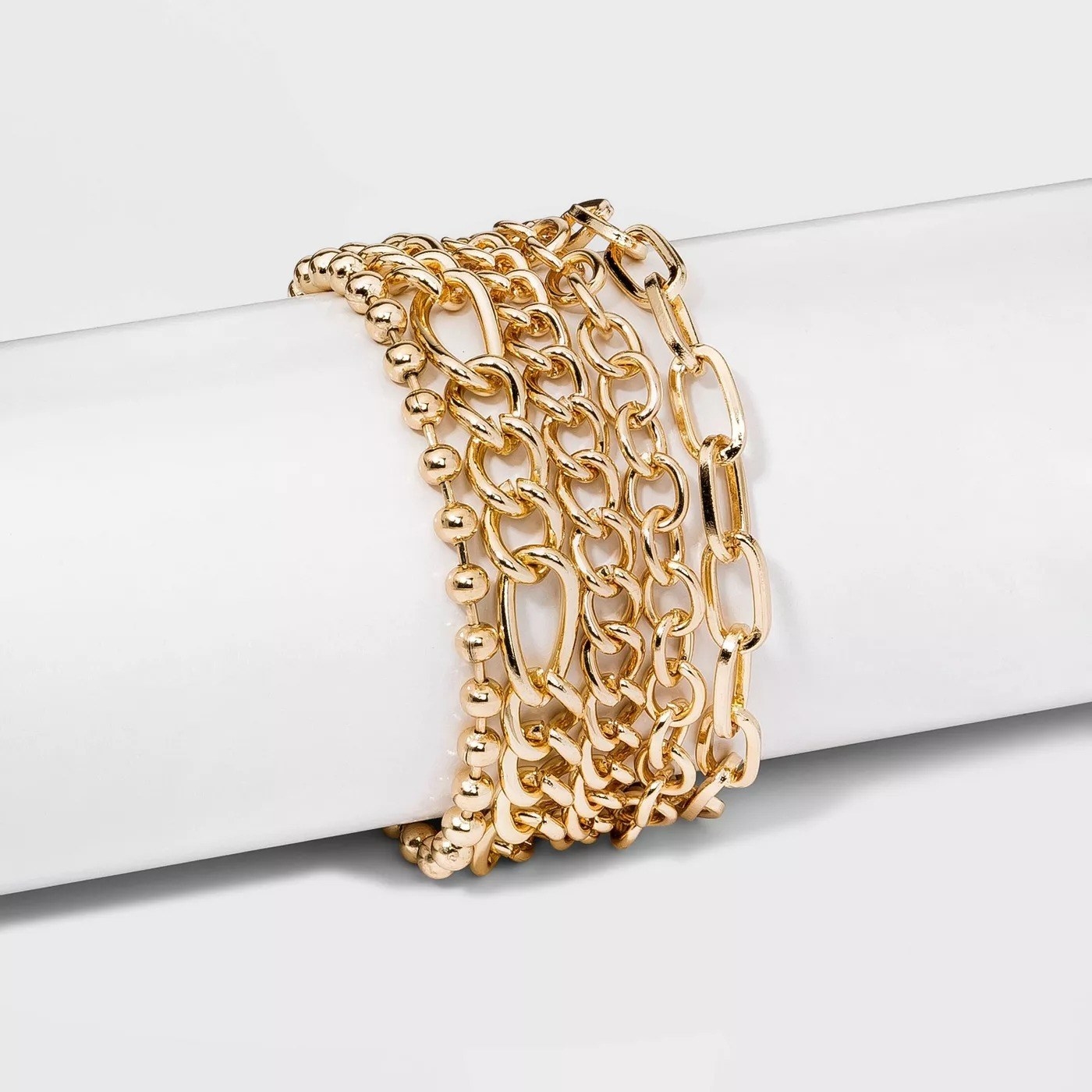 a gold stacked bracelet with five sizes of chains