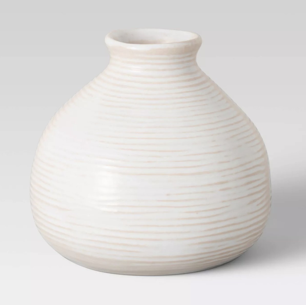 The white vase has a wide bottom and narrows toward the top and is covered in a semi-clear white glaze
