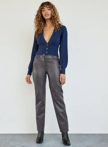 model wearing gray vegan leather pants with blue cardigan top