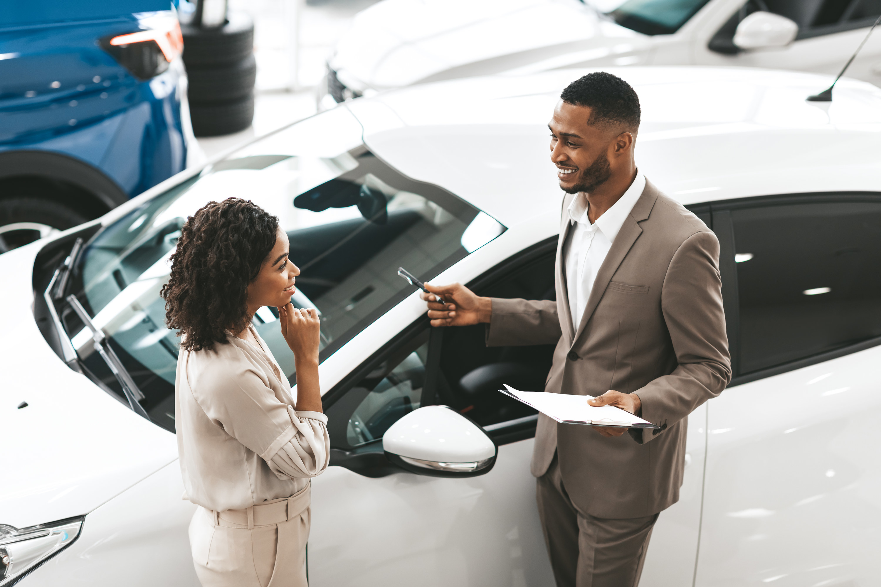 A man and a woman talking next to a white car