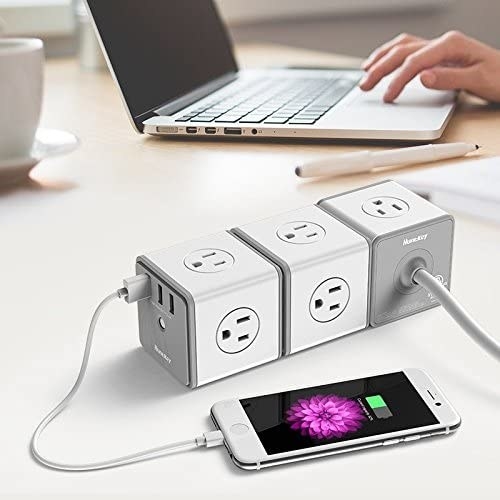 a trio of the cube-shaped plug splitters connected and charging a phone