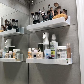 a reviewer photo of two shelves installed by a bathroom vanity and filled with various makeup and skincare products