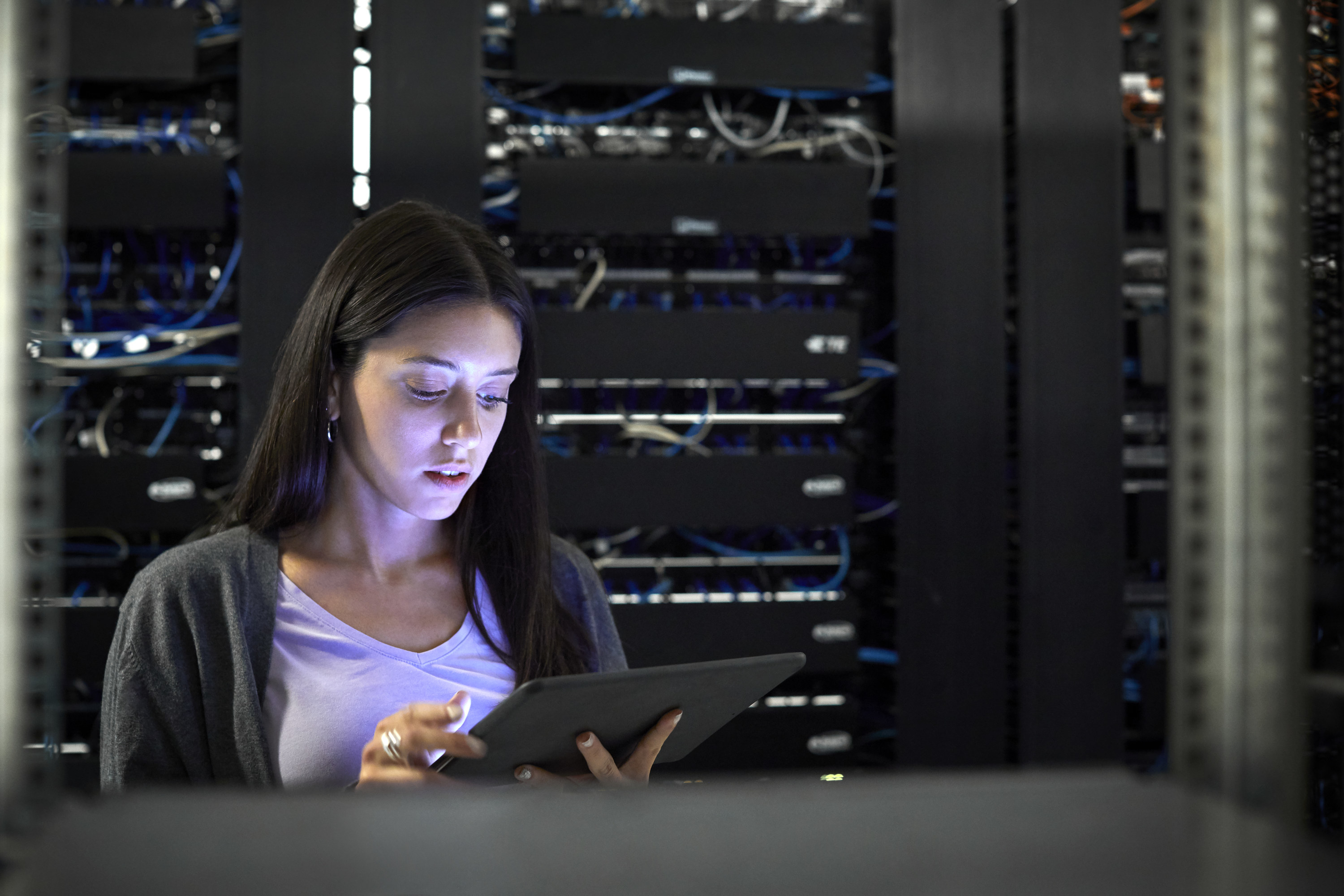 Woman looking at a tablet in a server room