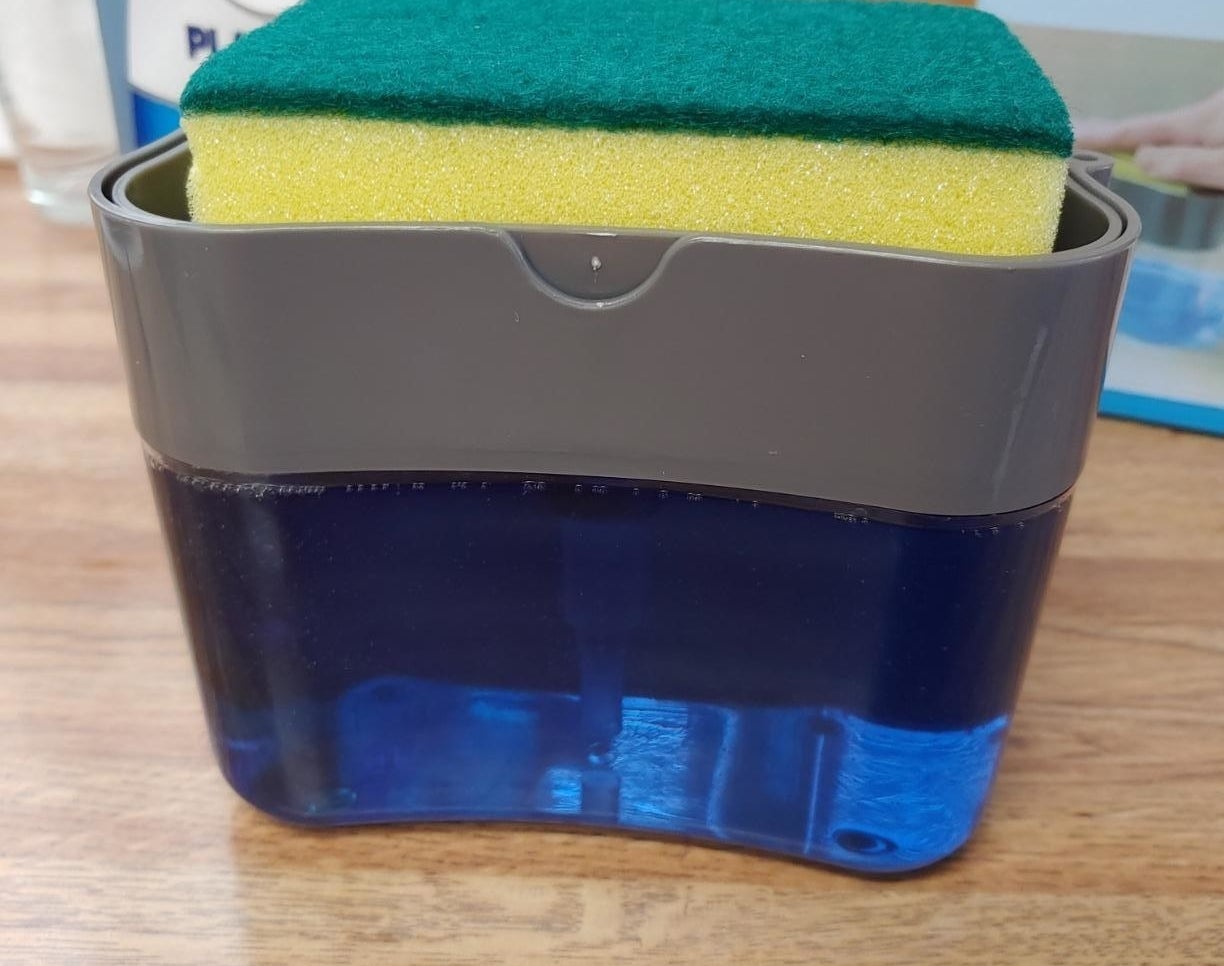 A sponge resting in the dispenser caddy that&#x27;s filled with dish soap