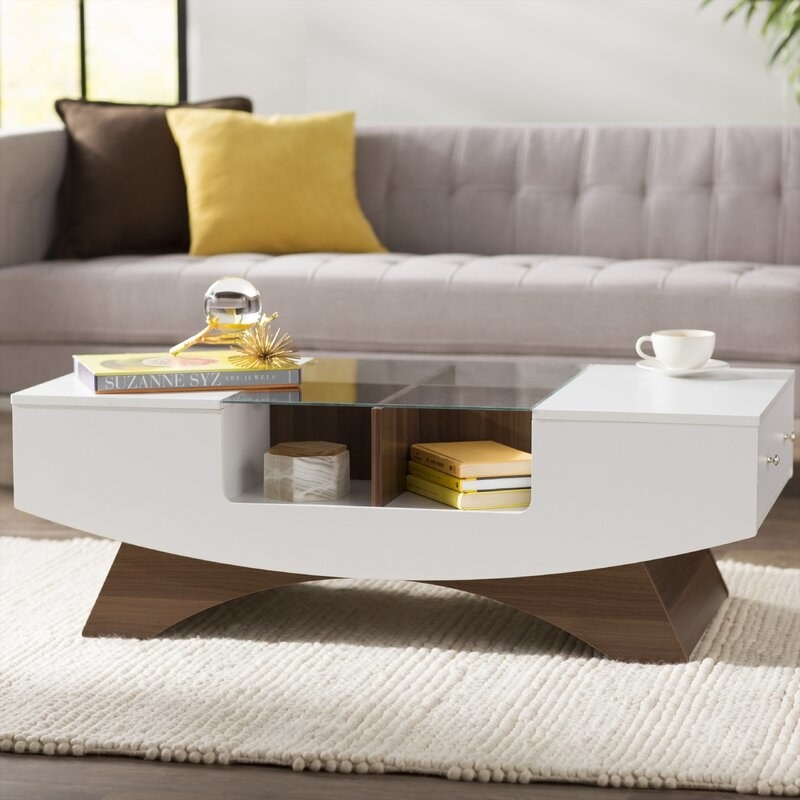 a white coffee table with wood legs and glass top