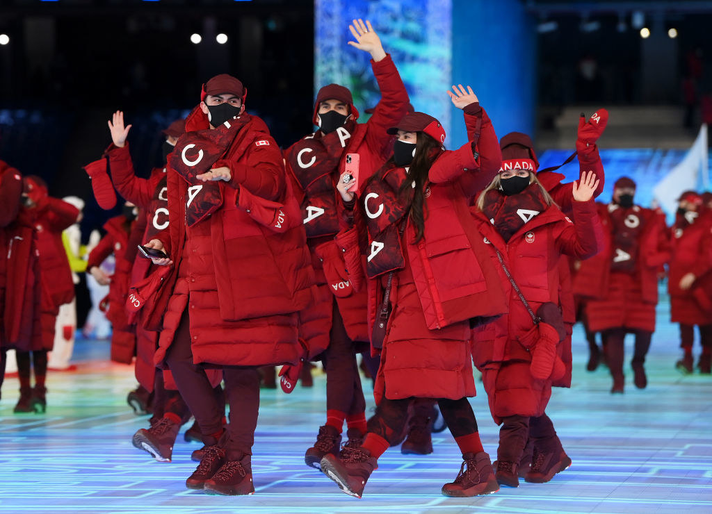 Members of Team Canada wave during the Opening Ceremony wearing all-red gear, which include a puffy jacket, huge scarves, and boots