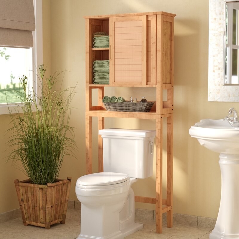 the bamboo over the toilet cabinet with sliding doors in a bathroom.