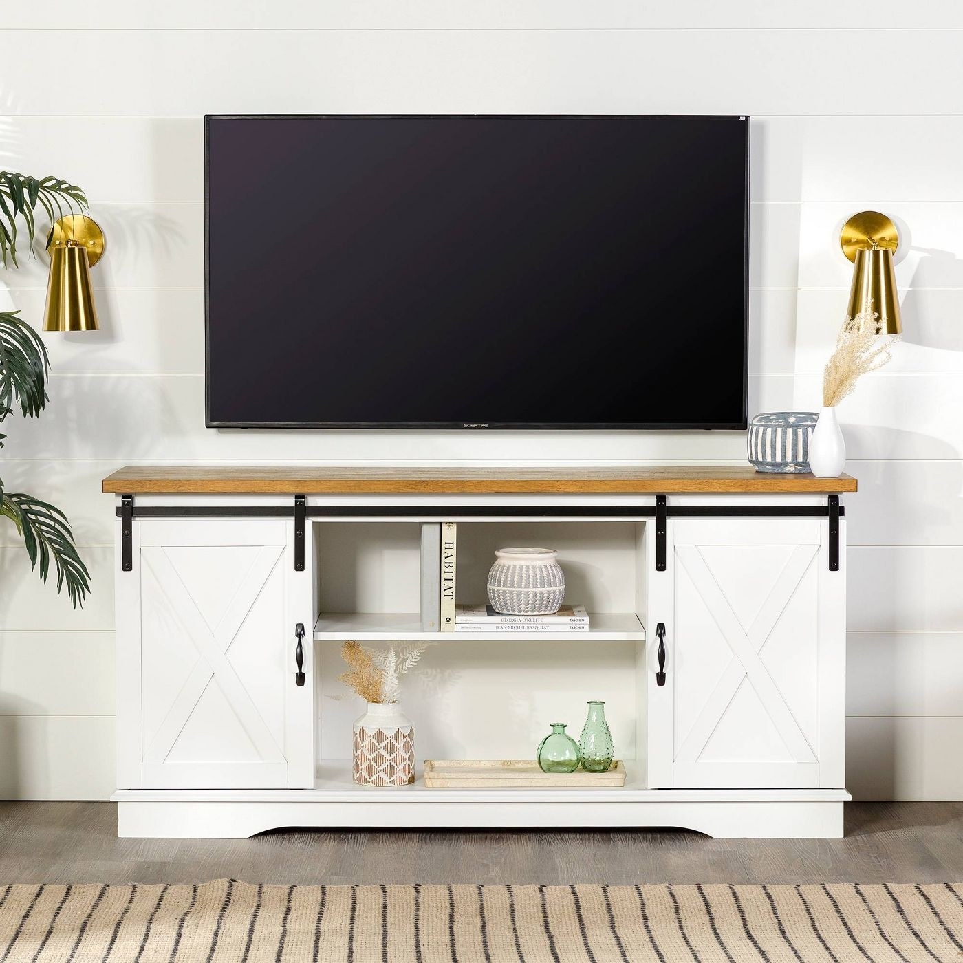 white sliding barn door TV stand with wood top below a TV hanging on wall