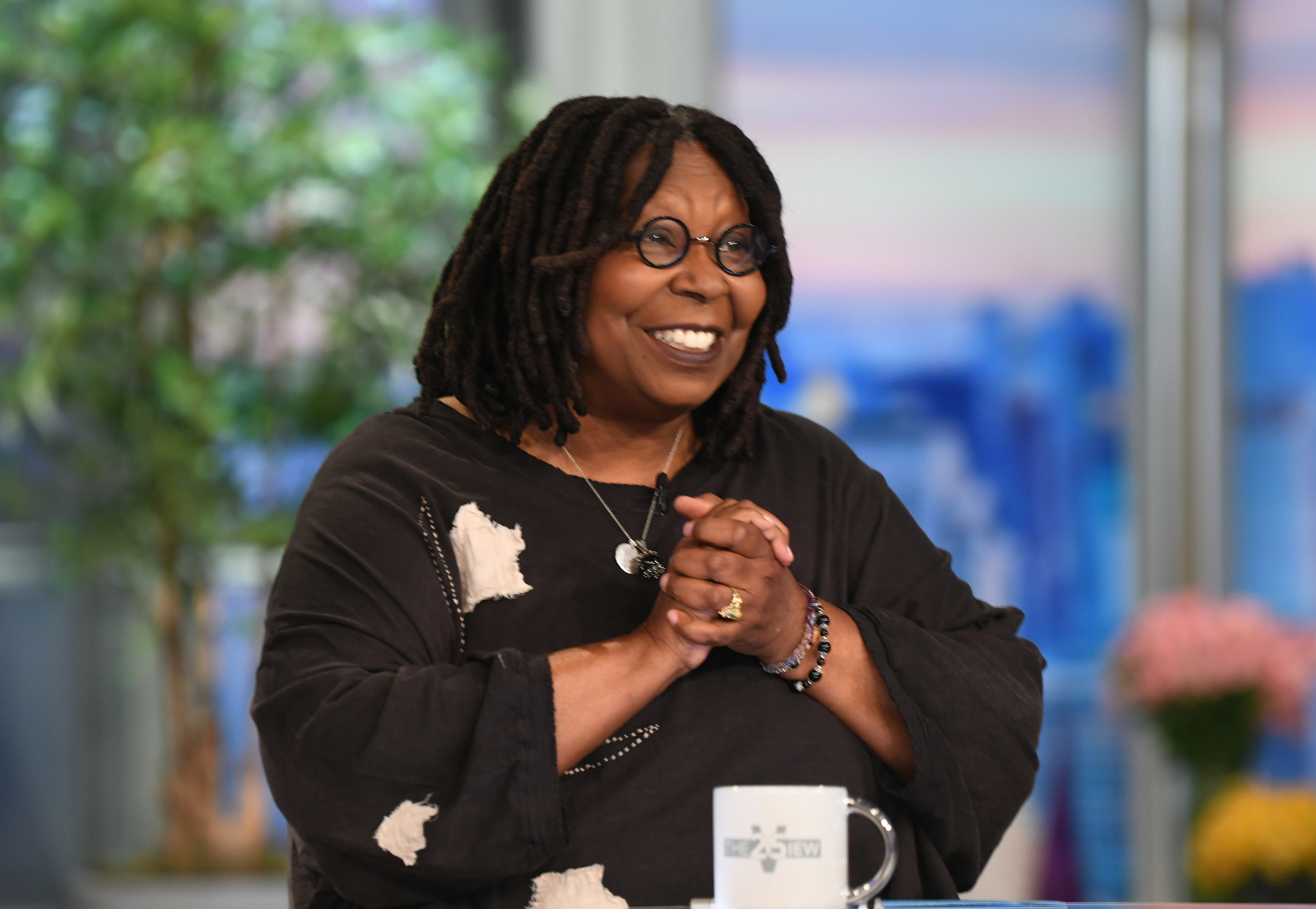 Whoopi Goldberg on "The View" with hands clasped together smiling