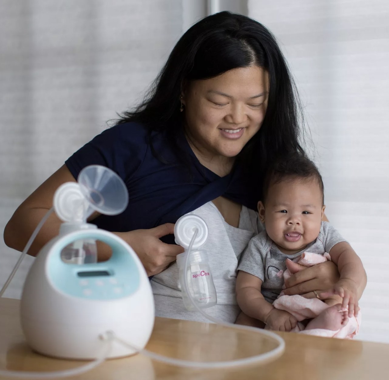 Mom using breast pump with baby