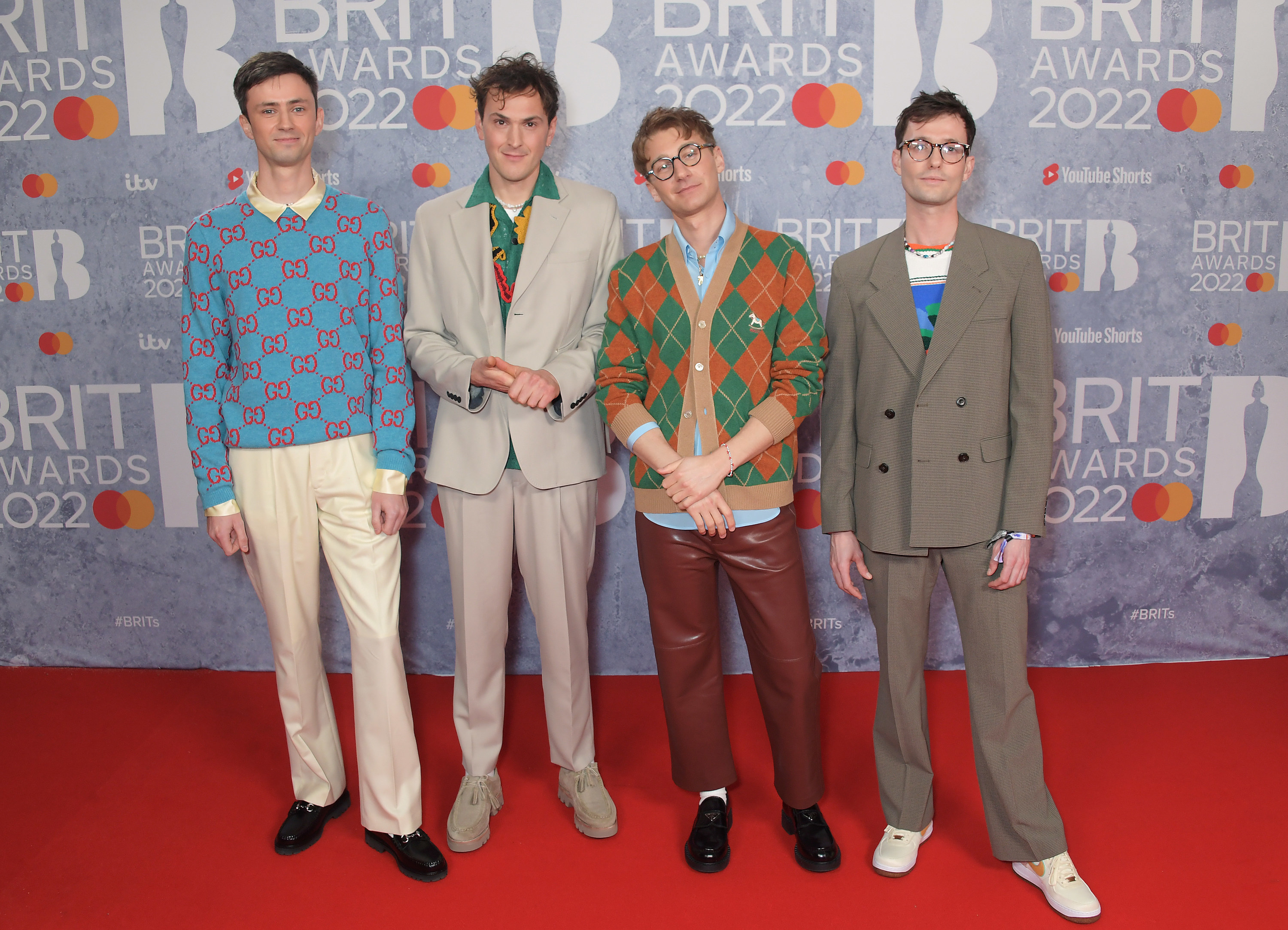 The band wears colorful sweaters and cardigans