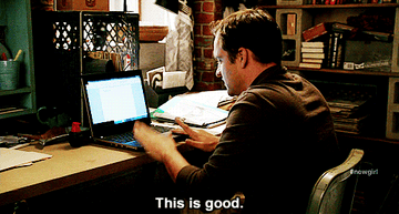 Nick Miller sits at his desk as he types on his laptop