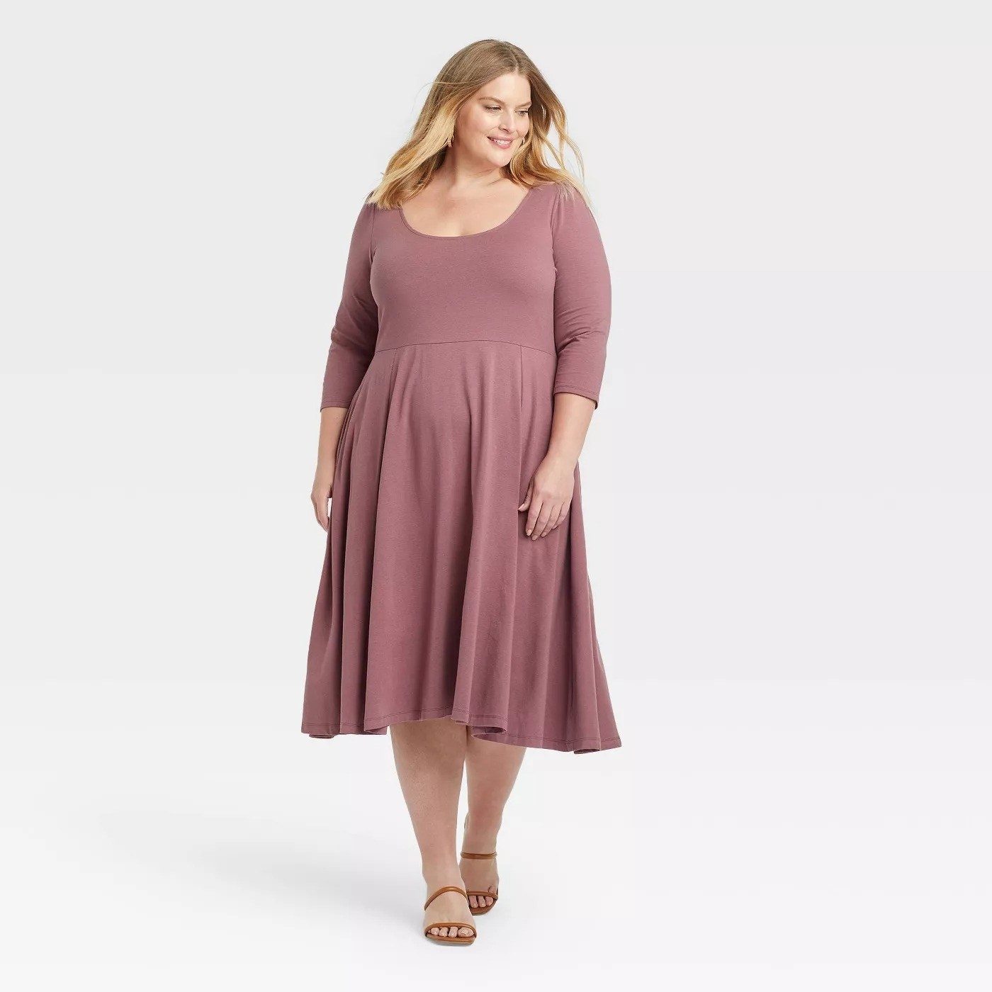 Model wearing mauve midi dress with round neck, goes past the knee
