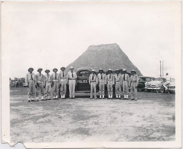 利昂·乔丹站在11人穿着警察制服,站在1950年代前警车在沙漠中