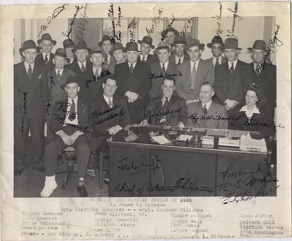 一大群堪萨斯城警察警察,大多数男人和一个女人——围聚在桌子上在1945年摆个姿势的照片