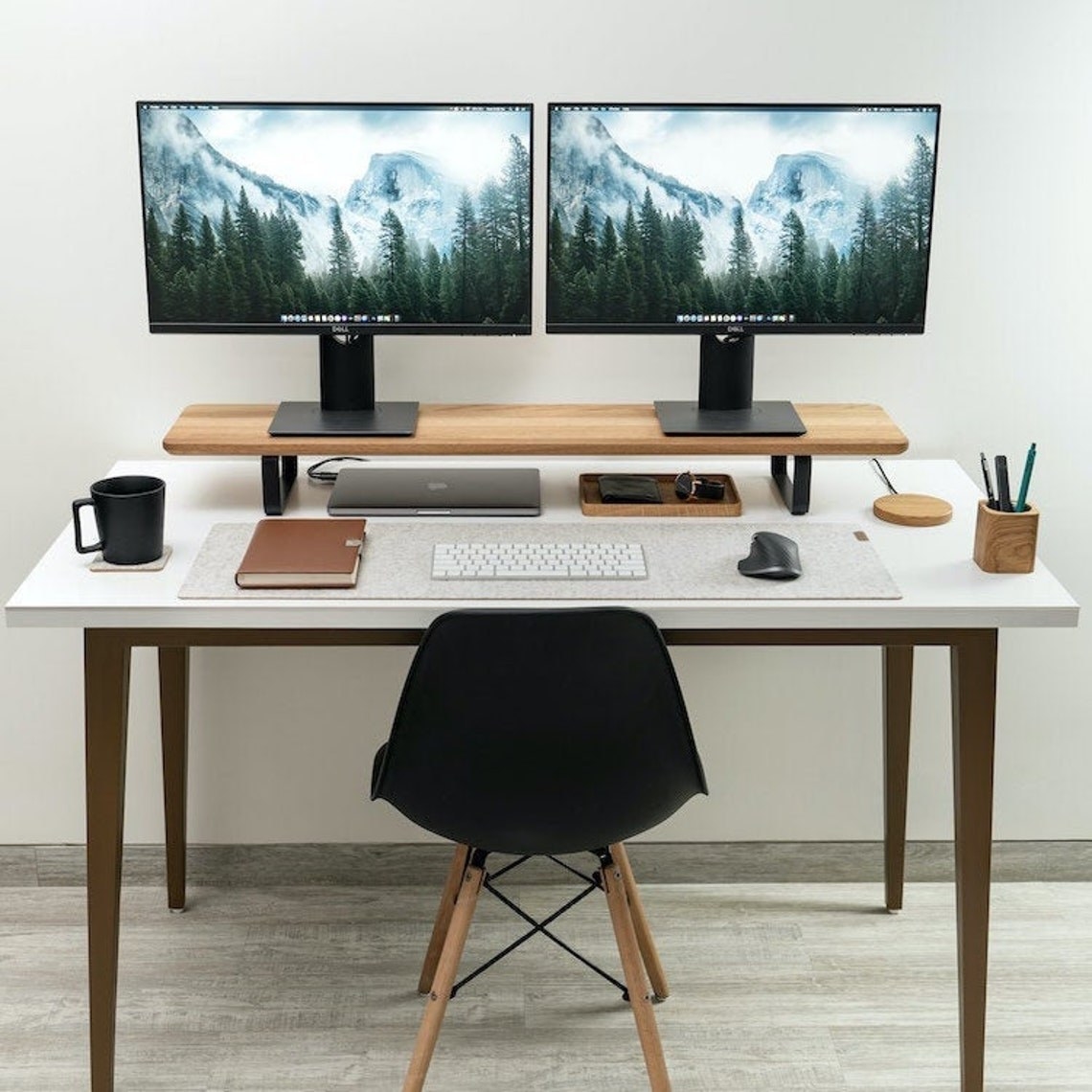 work desk with a wooden dual monitor stand with two monitors resting on it