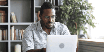 Man looks surprised and excited while on laptop