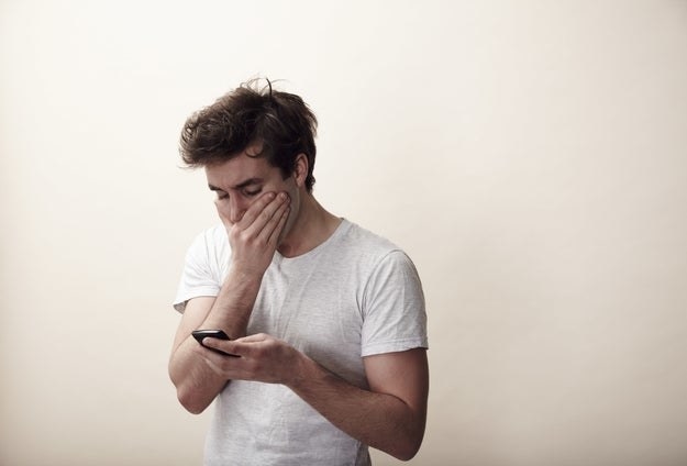 man covering his mouth in shock looking at his phone