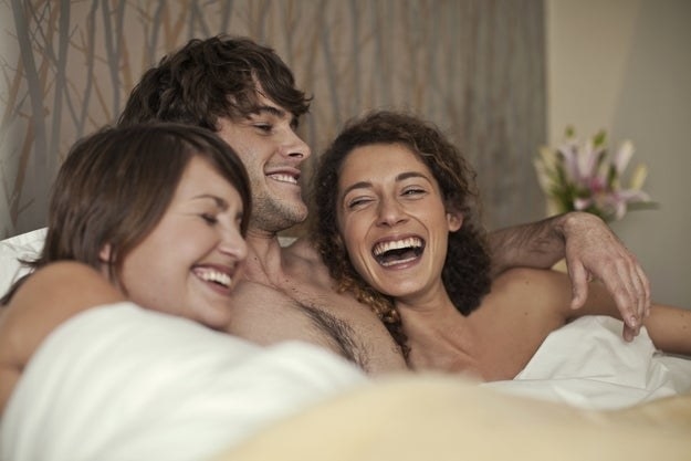 two women and a man in bed together
