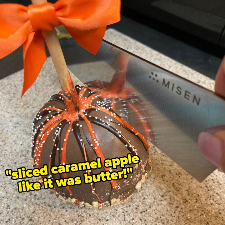 reviewer using the knife to slice through a refrigerated caramel apple with text overlaid "sliced caramel apple like it was butter!"
