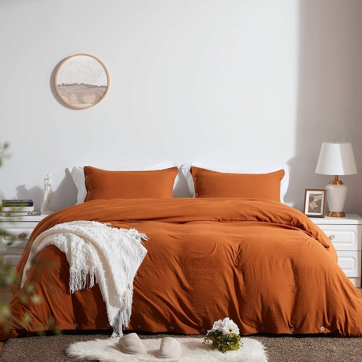 the orange duvet cover on a bed with a white throw on top