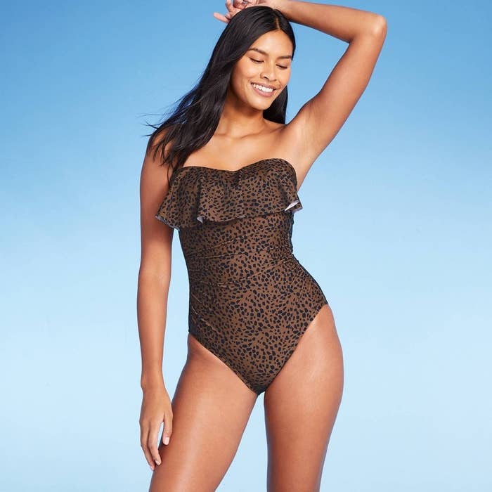 A person wearing a one-piece leopard print swimsuit