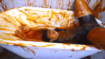 Person sliding around in a bathtub full of ketchup