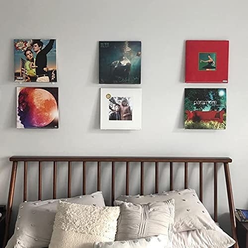 Six vinyl records hanging over a bed in a trendy bedroom