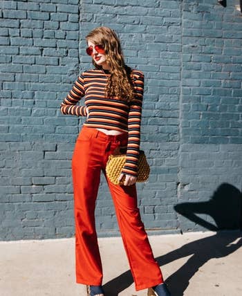 reviewer wearing the striped top with red pants