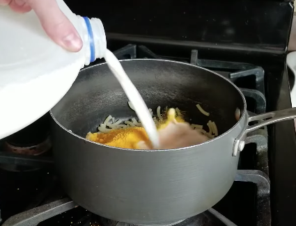 Adding milk to saucepan of Kraft mac &#x27;n&#x27; cheese on the stove