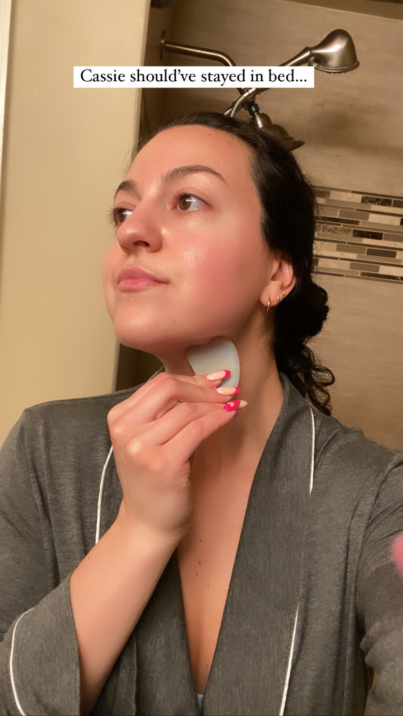 The author using a Gua Sha tool along her neck while she looks away to the side
