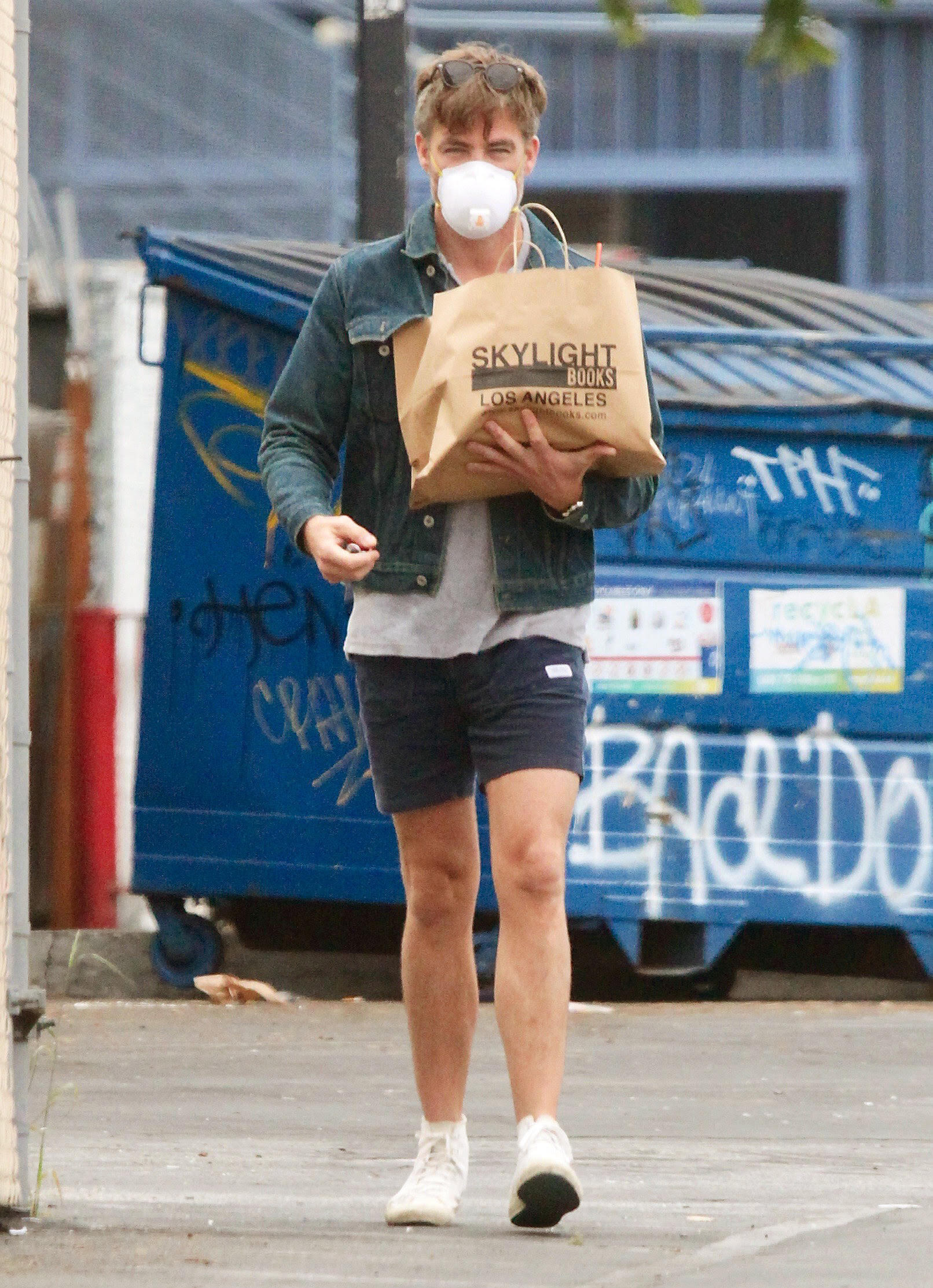 Chris Pine walking down the street with a bag of books