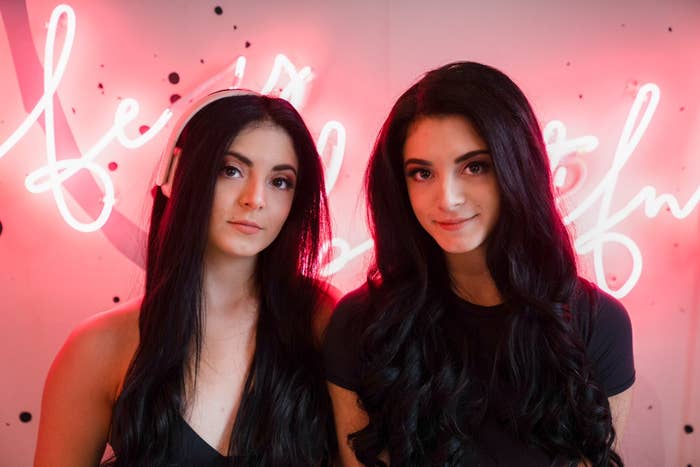 two women in front of an illuminated sign smiling