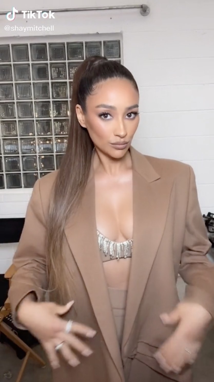 Shay looks at the camera straight on while wearing a blazer to cover her bump