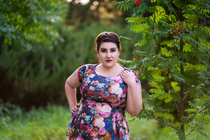 Plus size person wearing a floral dress in the woods