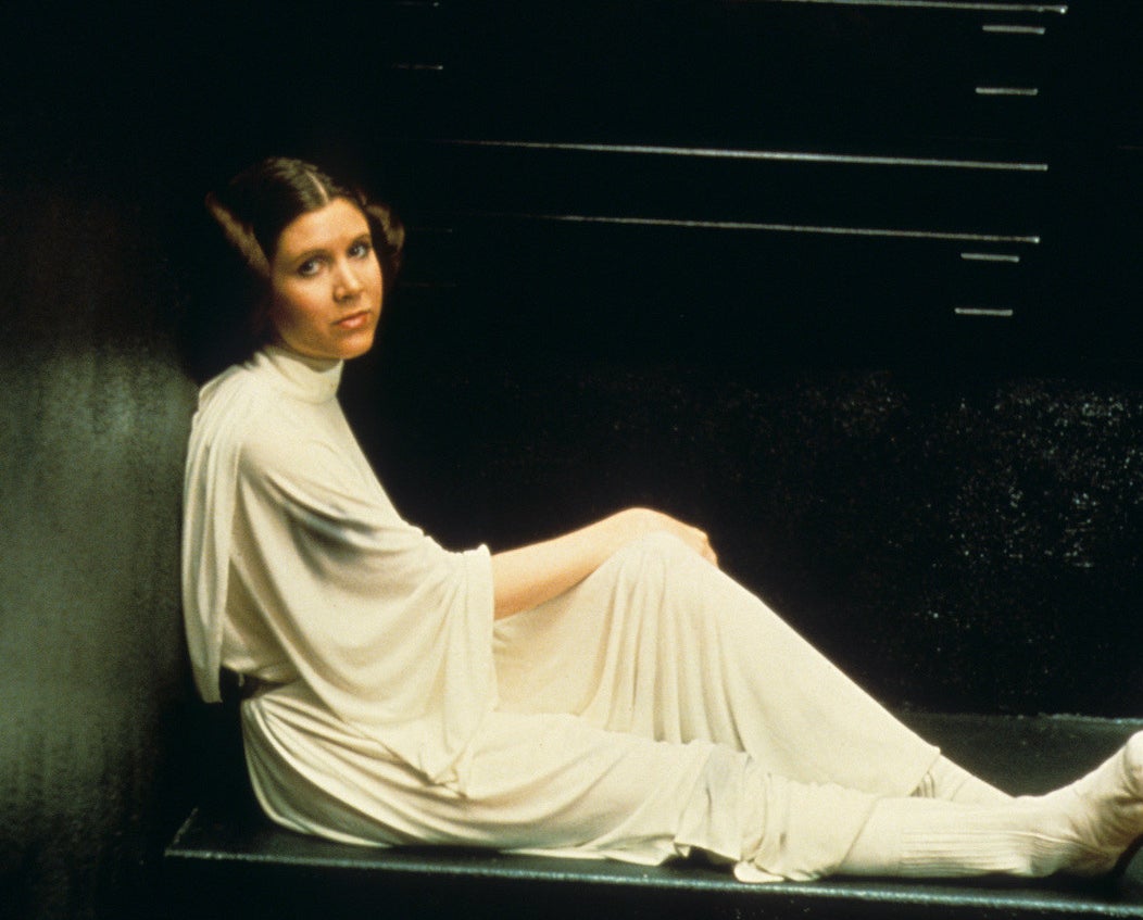 Princess Leia sits sideways and leans against a wall