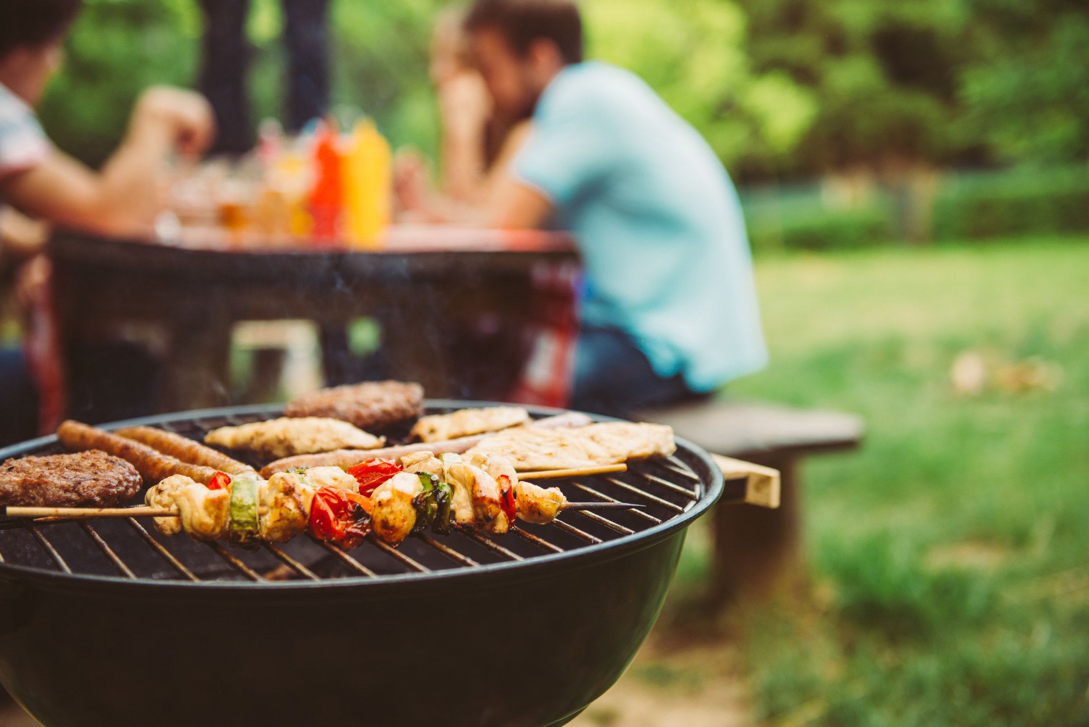 Friends making barbecue and having lunch in the nature.