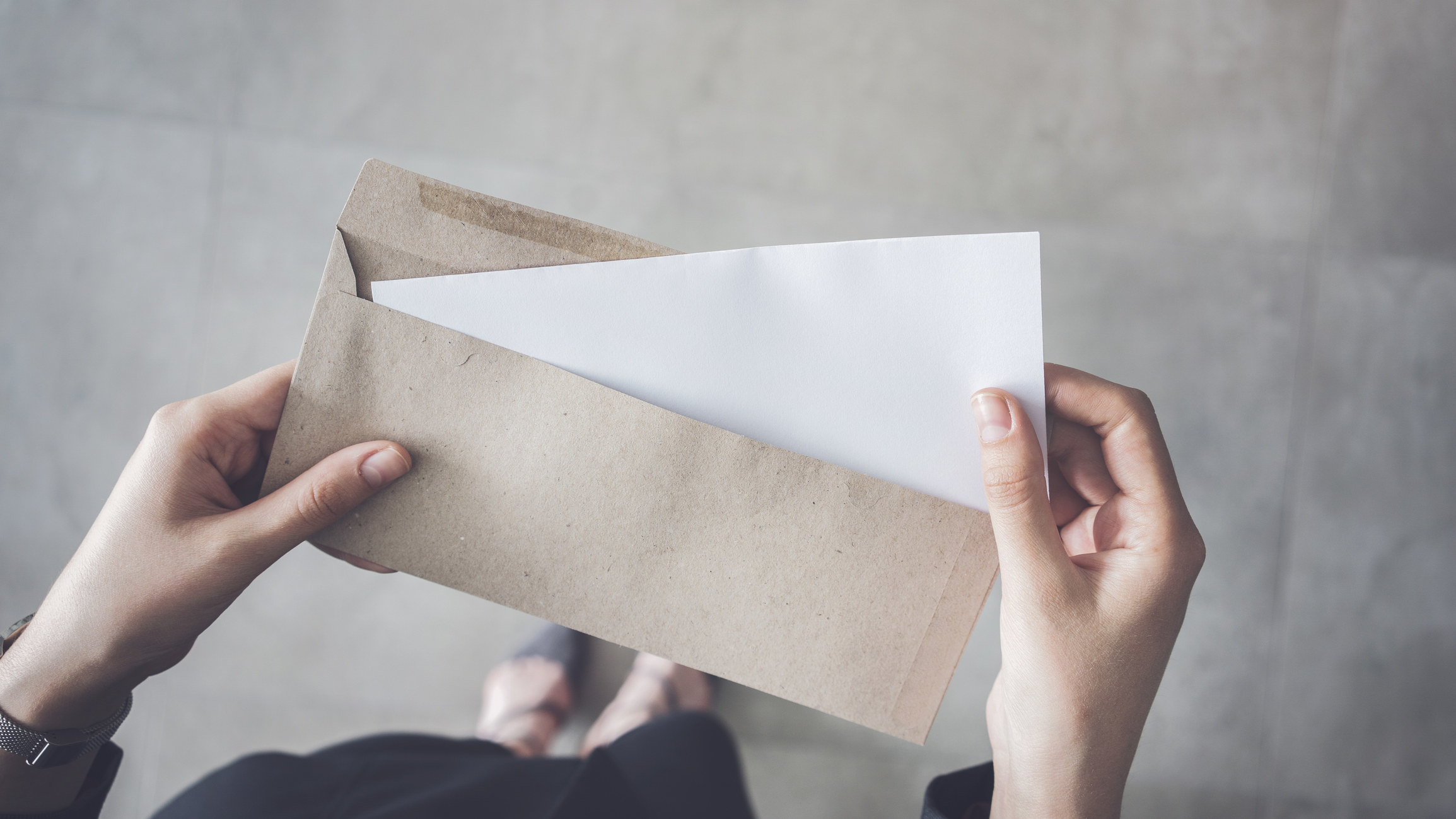 Hands hold white folded a4 paper and brown envelope