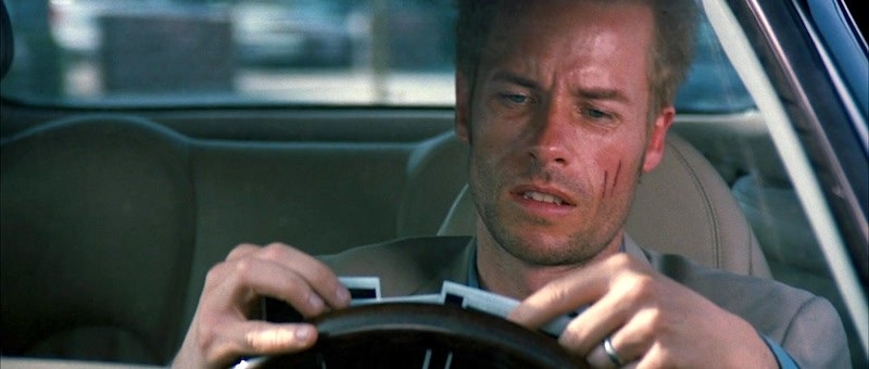 Guy Pearce as Leonard Shelby looking at Polaroids in his car