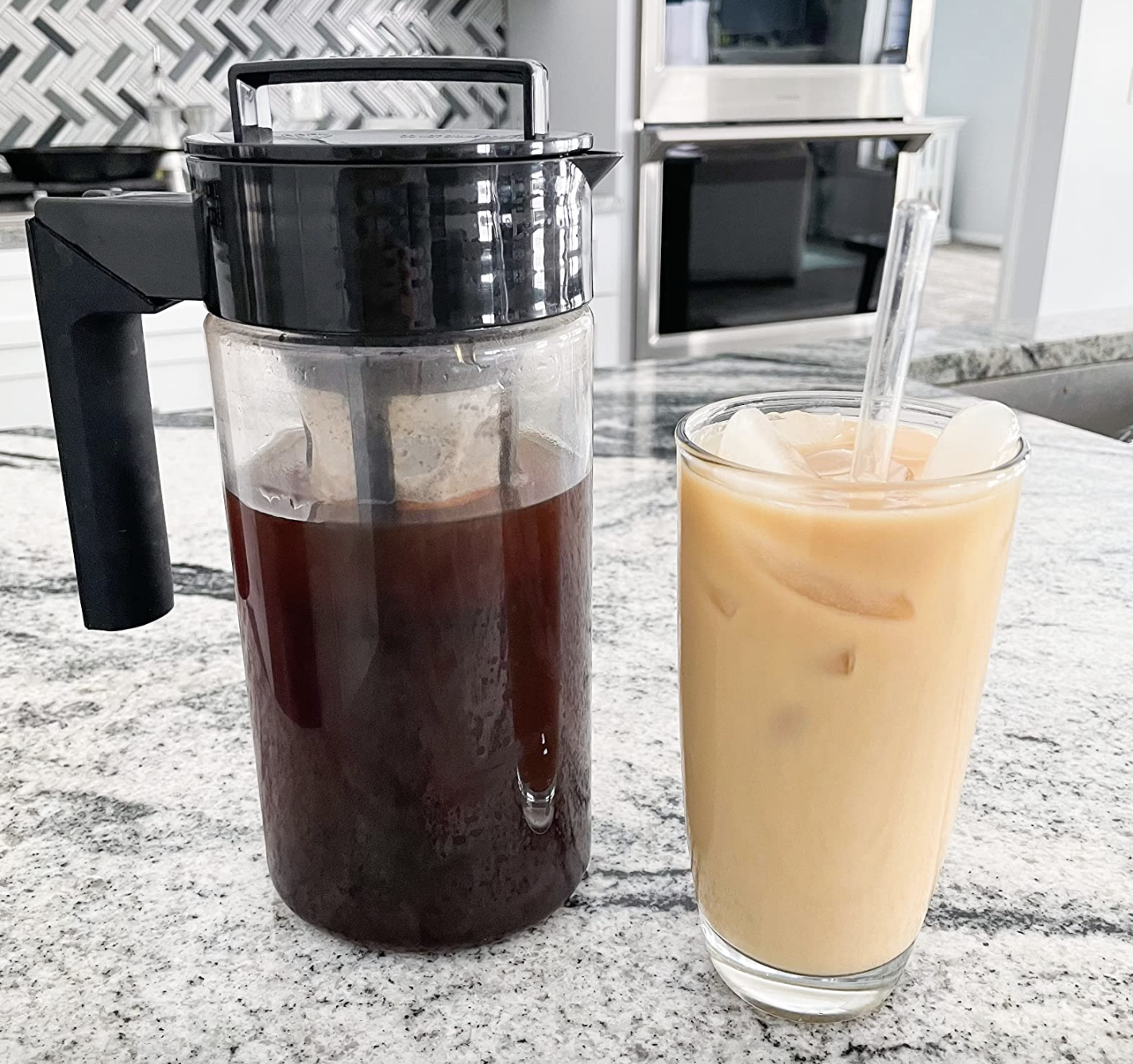 A customer review photo of their cold brew maker filled with coffee and next to a cup of cold brew mixed with ice and milk
