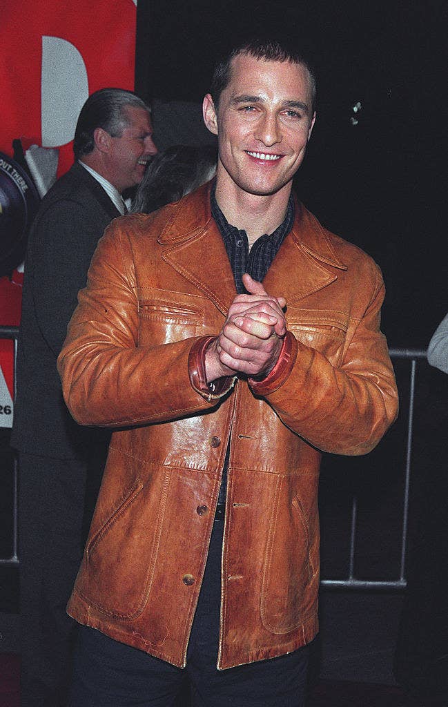 at a movie premiere in 1999, Matthew&#x27;s hair is cropped short, and he walks the red carpet wearing a heavy leather jacket over a dark shirt and pants
