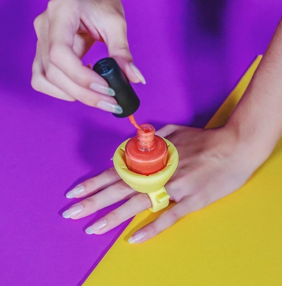 a person wearing the nail polish holder while painting their nails