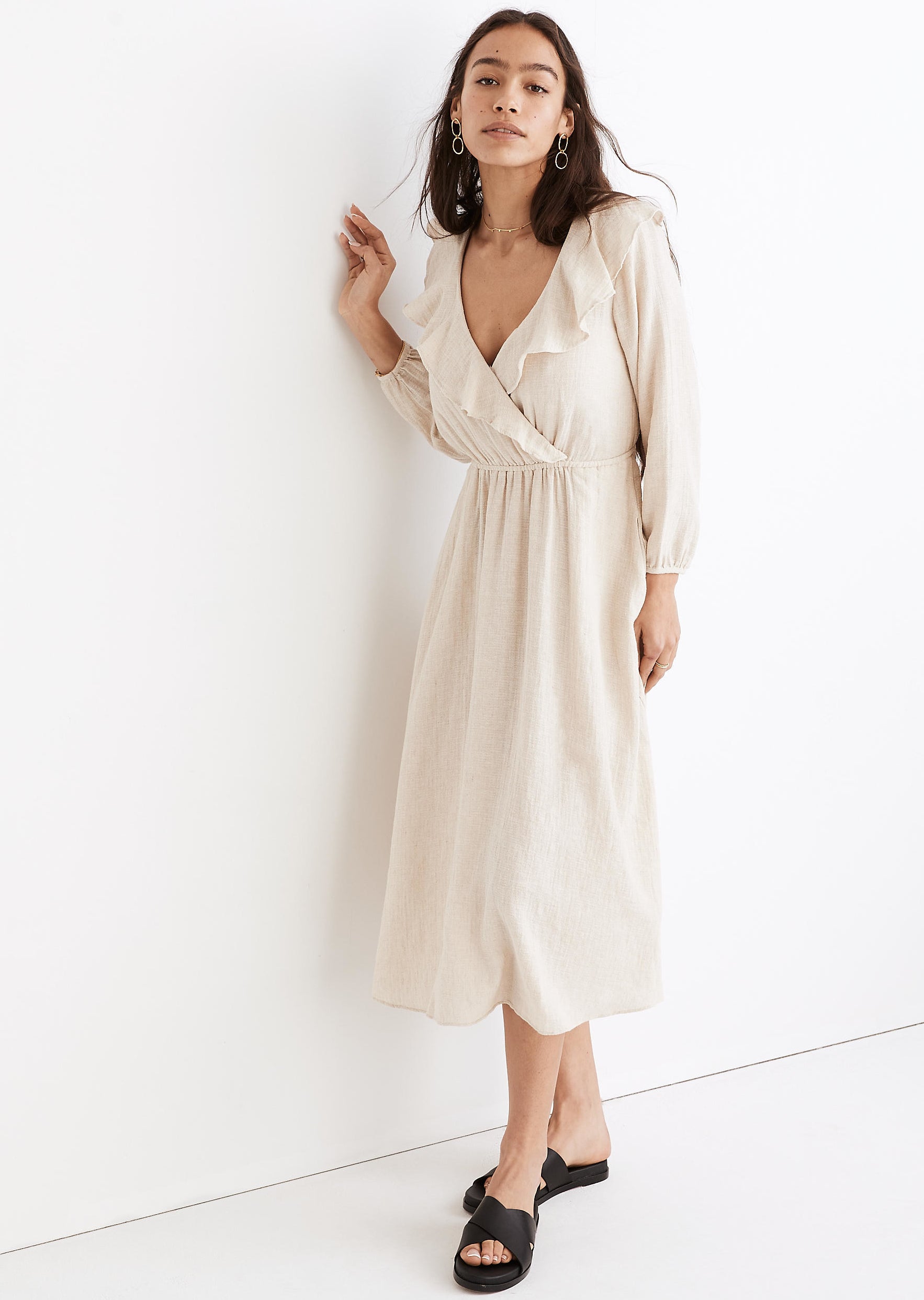 model in white v-neck midi dress with a layer of ruffles around the neckline and long sleeves with elastic at the wrists