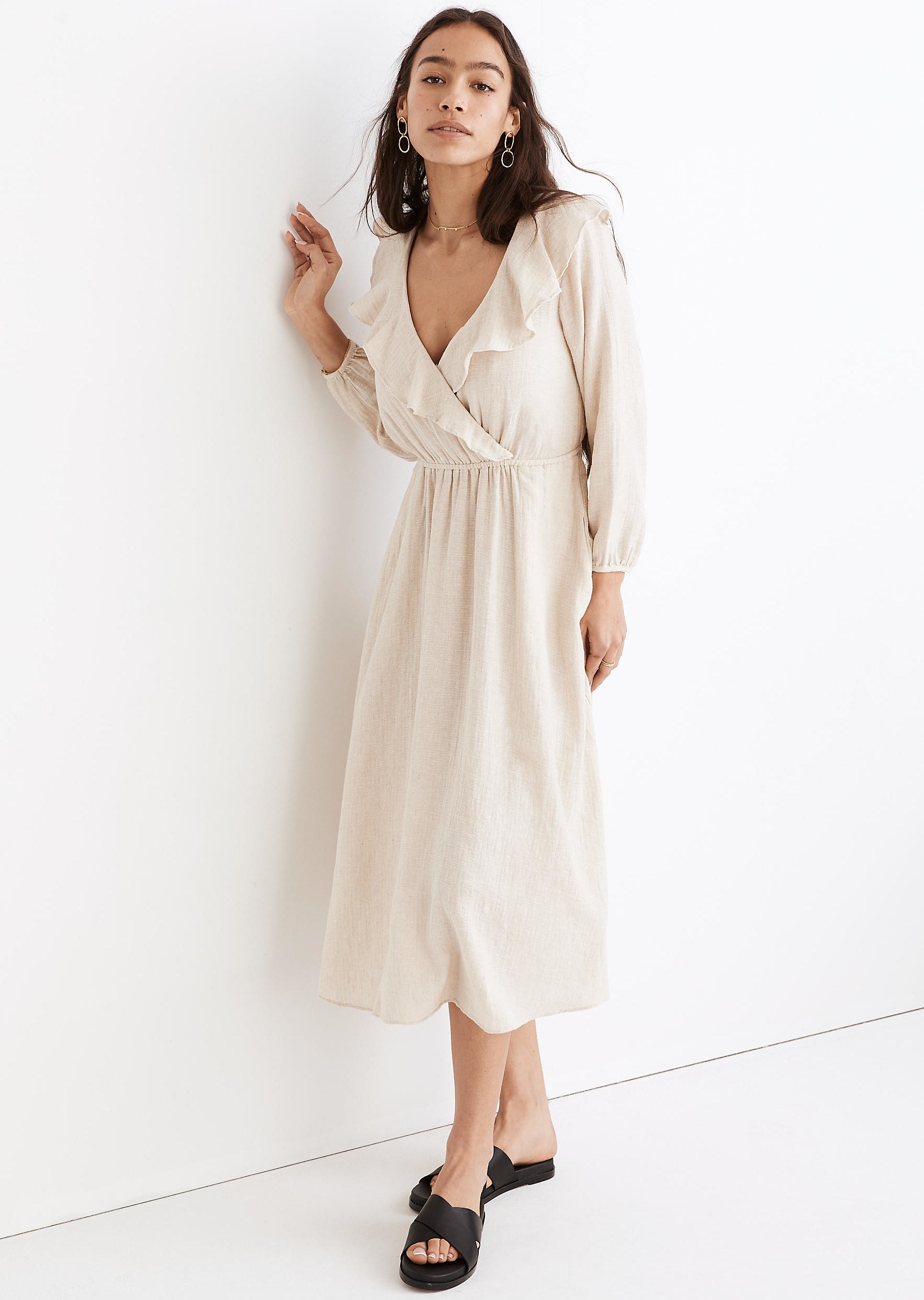 model in white v-neck midi dress with a layer of ruffles around the neckline and long sleeves with elastic at the wrists