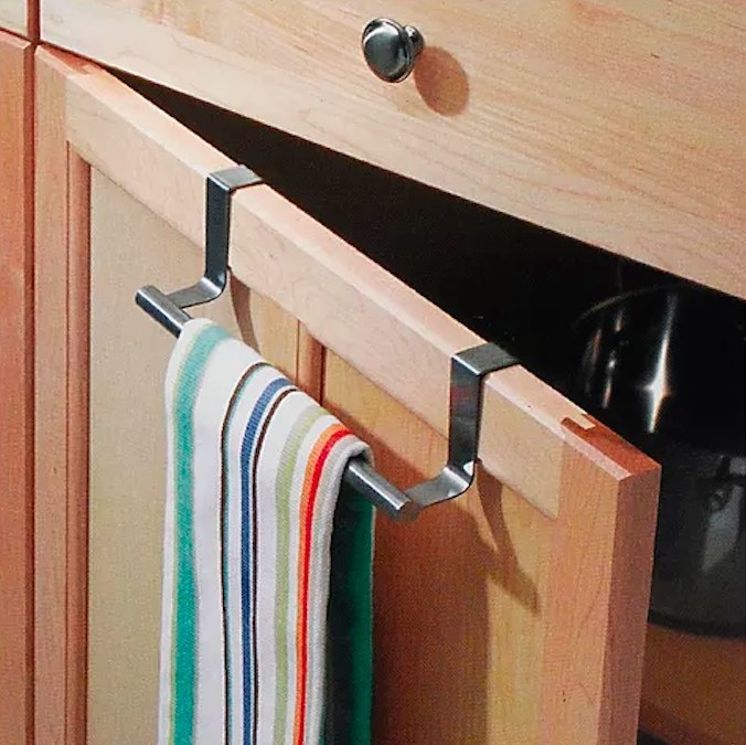 Towel bar with striped kitchen towel on a wood cabinet door