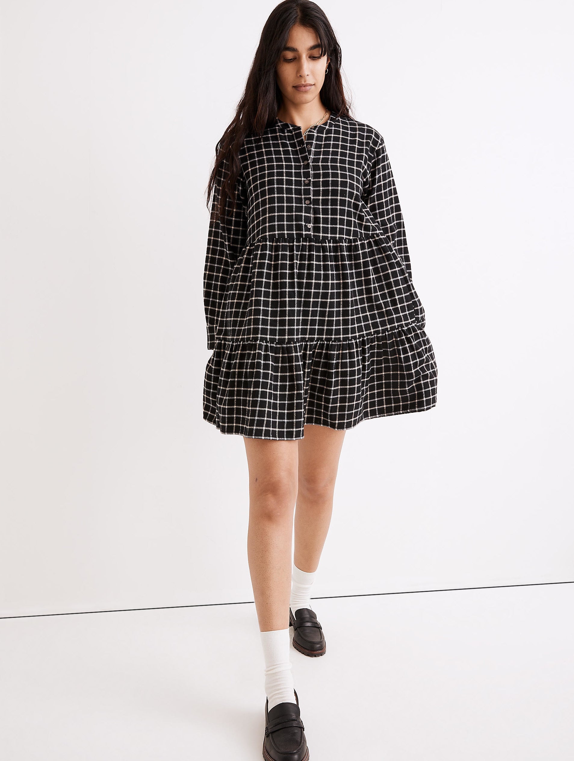 model in a short tiered black dress with a thin white checker pattern