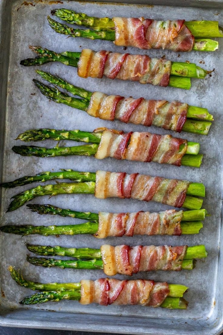 Bacon-wrapped asparagus on a baking sheet.