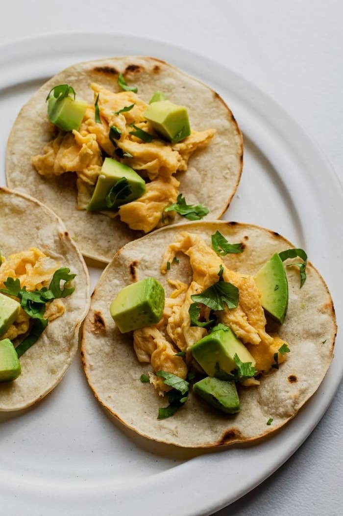 Avocado and scrambled egg tacos on a plate.