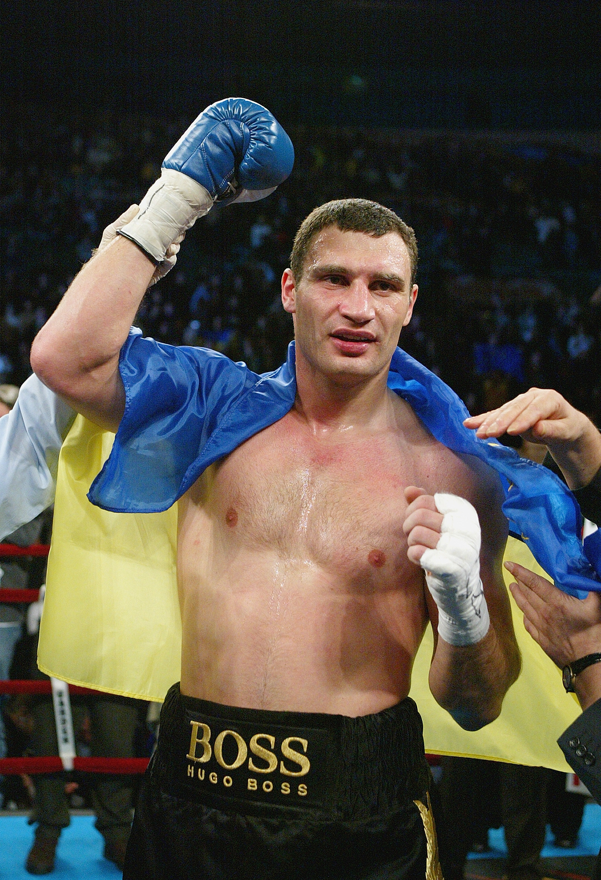 Vitali Klitschko in boxing ring with a Ukraine flag draped over his shoulders