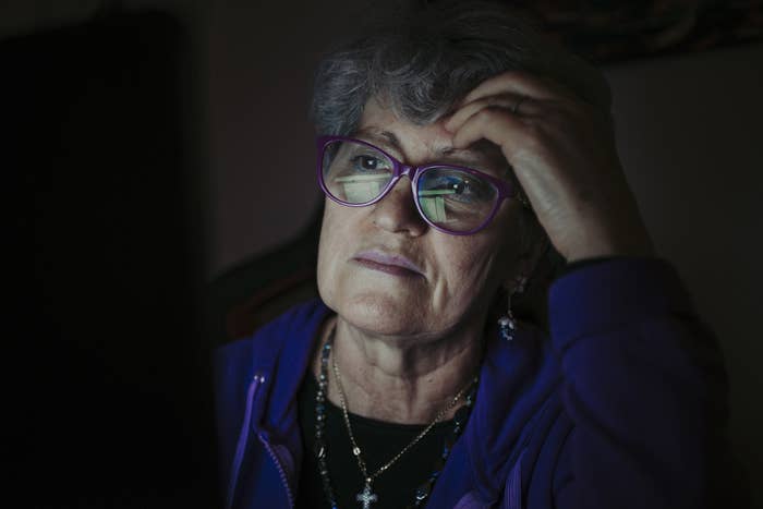 an old woman looking at a computer screen in the dark
